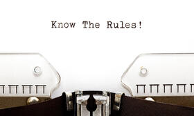 The picture shows a sheet of paper clamped in a typewriter with Know The Rules on it.